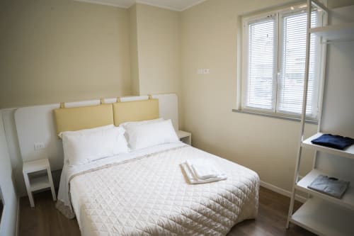 Bright bedroom at Residence Balconi del Conero with white bed, yellow headboard, and courtyard view near Marcelli