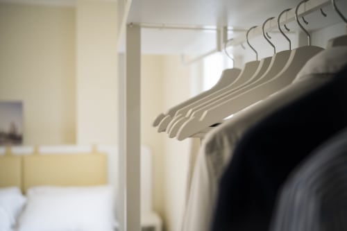 White coat hangers on rod in bright apartment bedroom at Residence Balconi del Conero, Marcelli