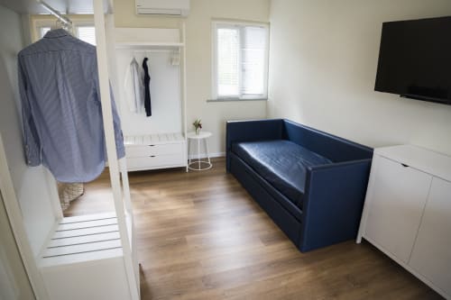 Accessible apartment bedroom with blue sofa bed, flat-screen TV, wardrobe, and wooden flooring at Residence Balconi del