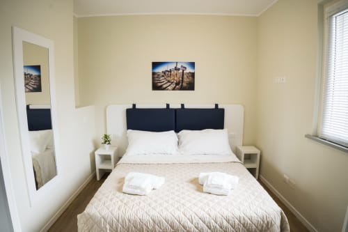 Accessible bedroom at Residence Balconi del Conero in Marcelli with double bed, white nightstands, and courtyard view