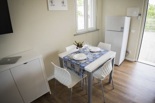 Accessible apartment dining area at Residence Balconi del Conero with set table, white chairs, kitchenette, and refrigerator