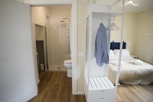 Accessible apartment hallway with bathroom, bedroom with double bed, and wooden flooring at Residence Balconi del Conero