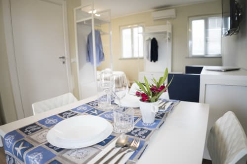 Dining area in accessible apartment at Residence Balconi del Conero with set table, flowers, and kitchen visible