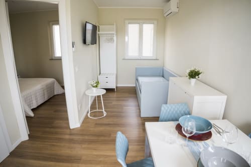 Modern apartment living space with dining area, sofa bed, kitchenette, and bedroom at Residence Balconi del Conero in