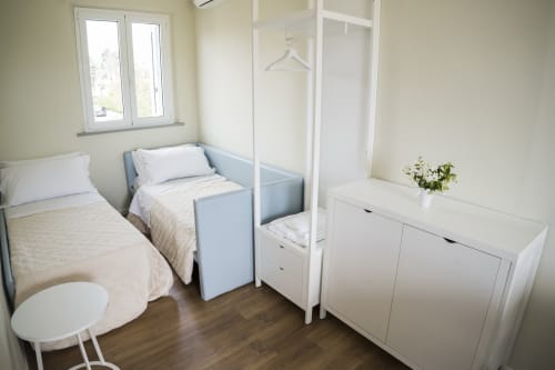 Bright, minimalist bedroom with two single beds, white wardrobe, and sea view window at Residence Balconi del Conero,