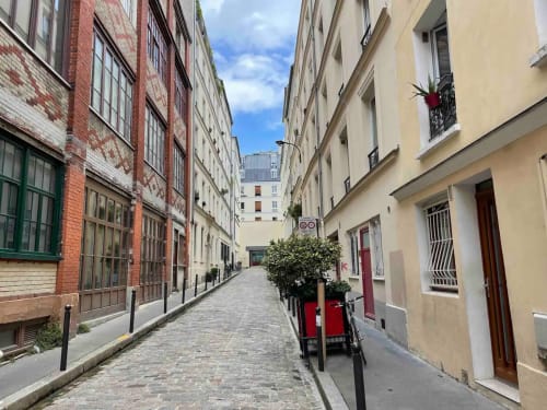 Charmante rue parisienne avec bâtiments historiques, porte rouge et pavés près de l'hôtel Chez Adrien Paris