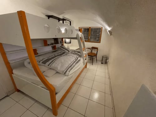 Chambre lumineuse avec lits superposés chez Adrien Paris, cadres en bois orange, murs blancs et carrelage à Paris.
