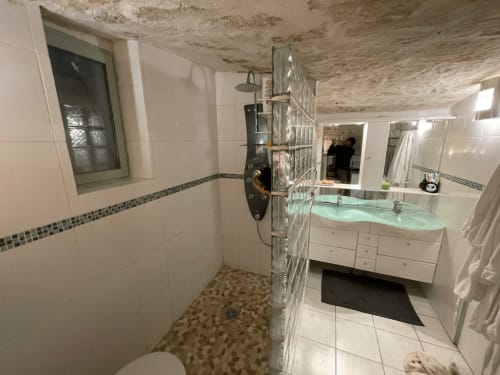 Salle de bain moderne à Chez Adrien Paris avec douche à l'italienne, vasque, carrelage blanc et plafond endommagé