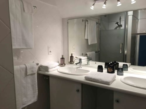 Salle de bain Bergamote du Manoir De Rieuzal, LOUBRESSAC, avec double vasque, douche, porte-serviettes et articles de toilette