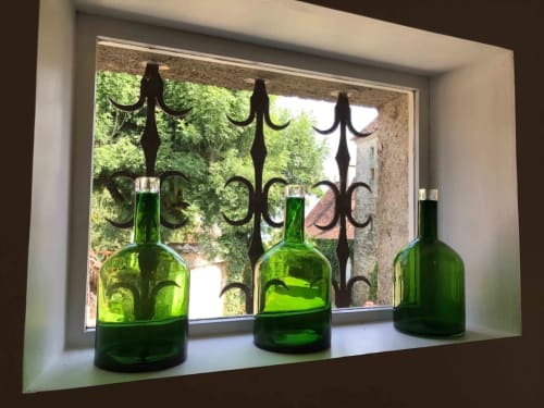 Bouteilles de vin vert sur le rebord de fenêtre au Manoir de Rieuzal, avec grille de fer forgé ornementale et vue sur Loubressac