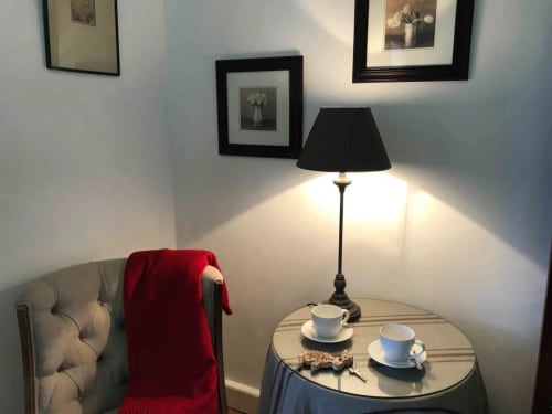 Coin salon cosy de l'appartement Bergamot au Manoir De Rieuzal avec lampe, service à thé et tableaux encadrés
