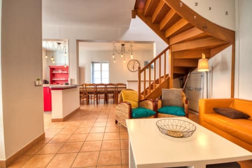 Salon du cottage Le Chêne à Vacances en Touraine avec escalier en bois, canapé orange, salle à manger et cuisine ouverte