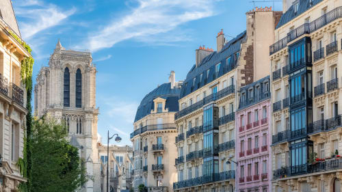 Vue d'une rue parisienne avec la tour de Notre-Dame, des immeubles haussmanniens historiques et façades lierre près de Chez Adrien
