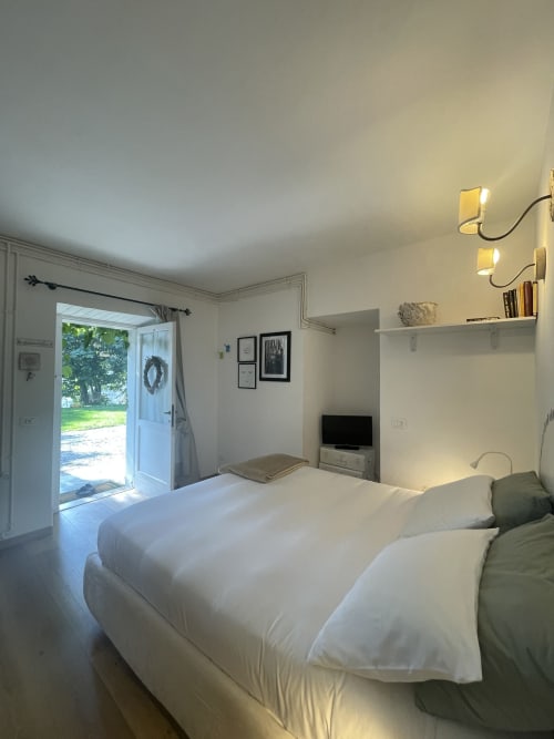 Bright Wisteria Double Room at La Cascina di Bea B&B with garden view, white bedding, flat-screen TV, and open patio doors in