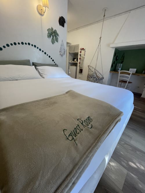 Wisteria Double Room at La Cascina di Bea B&B in Bergamo with comfortable bed, wooden flooring, hanging chair, and botanical