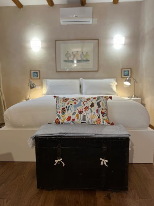 Bright, modern double bedroom at La Cascina di Bea with white bed, colorful pillow, black bench, wall art, and air
