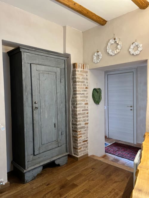 Entryway of Iris Double Room at La Cascina di Bea B&B in Bergamo, with gray armoire, exposed brick column, and modern door