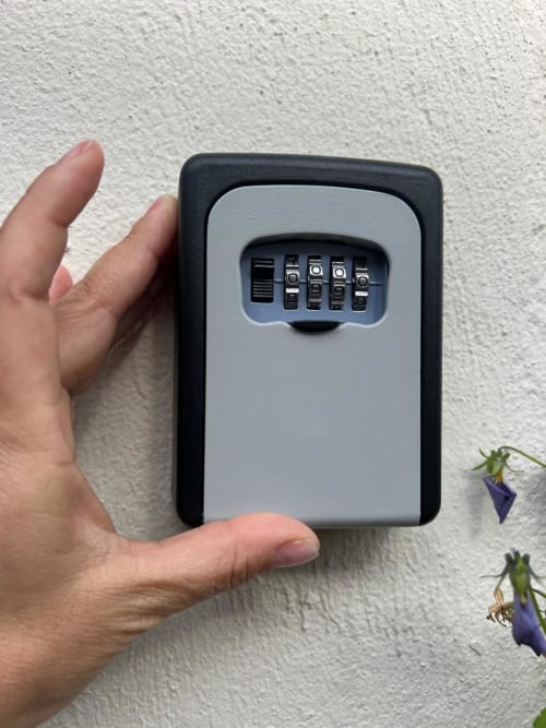 Hand holding wall-mounted key lock box at La Cascina di Bea BnB in Torre Boldone, Bergamo