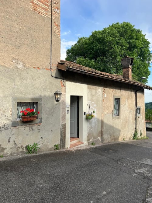 Charming stone cottage entrance at La Cascina di Bea, Bergamo, with red geraniums and green door