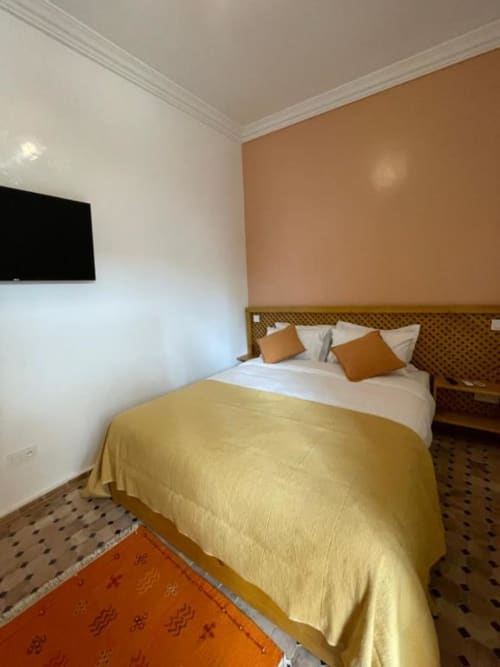 Chambre au Riad Madinina à Marrakech avec lit queen-size, plaid doré, accents orangés et murs pêche