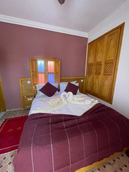 Chambre cosy du Riad Madinina à Marrakech avec literie bordeaux, portes en bois, murs roses et décor traditionnel