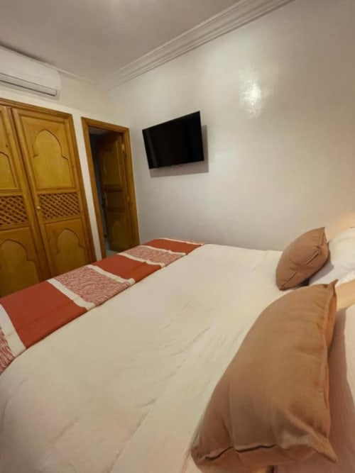 Chambre avec lit jumeau à la Riad Madinina de Marrakech, portes en bois et TV murale