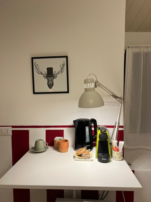 Modern desk workspace at La Cascina di Bea with lamp, coffee machine, and framed deer art in Dalia room, Torre Boldone,