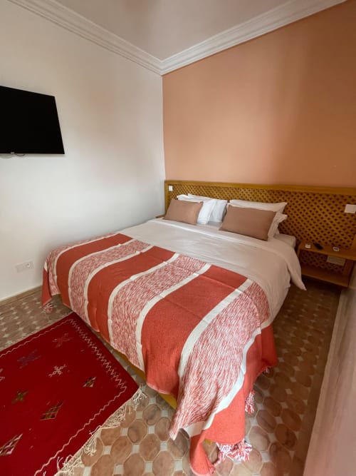 Chambre au Riad Madinina, Marrakech : murs en terre cuite, literie rayée, vue sur la ville