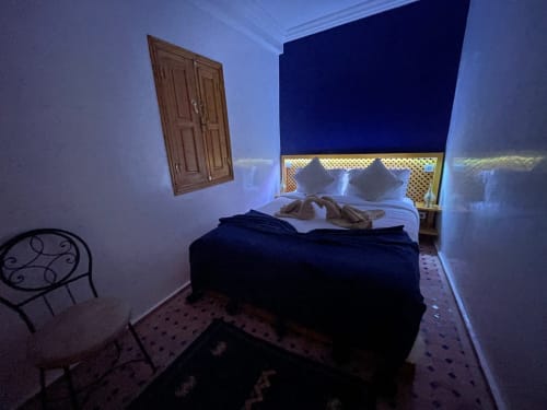 Cozy bedroom at Riad Madinina in Marrakech with blue walls, bed, wooden wardrobe, and city view from window