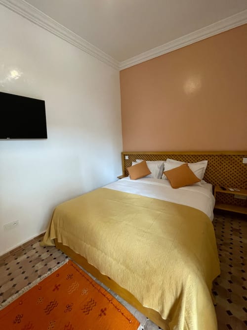 Chambre d'hôtel moderne au Riad Madinina à Marrakech avec literie jaune, murs terre cuite et vue sur la ville