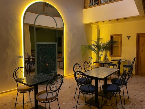 Cour du Riad Madinina avec portail néon voûté, tables de salle à manger et décoration marocaine à Marrakech