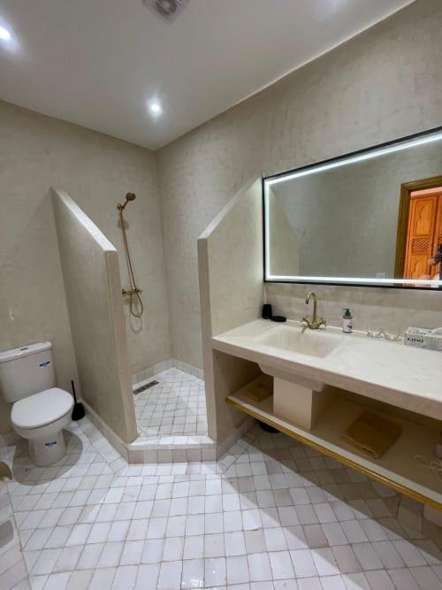 Salle de bain moderne du riad Madinina à Marrakech avec douche, lavabo, toilettes et miroir éclairant