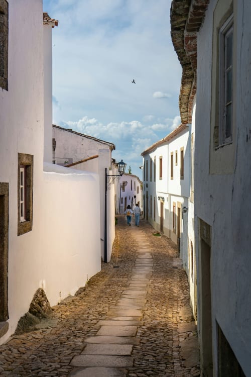 Charming cobblestone street in Juromenha with whitewashed historic buildings and blue sky