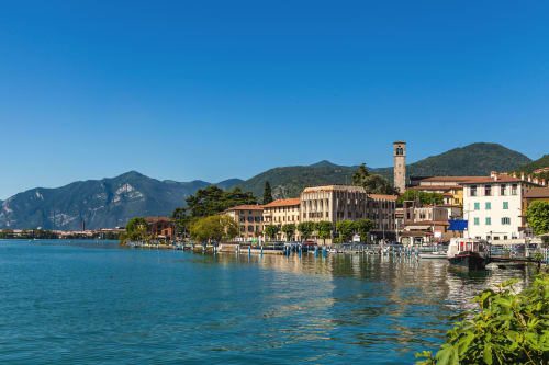 Scenic lakeside view of Italian waterfront town with colorful buildings and mountains