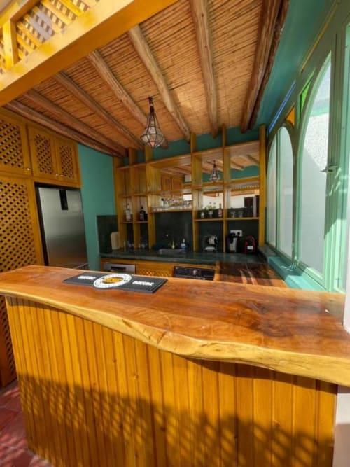 Riad Madinina bar with wooden counter, green walls, and traditional Moroccan design in Marrakech