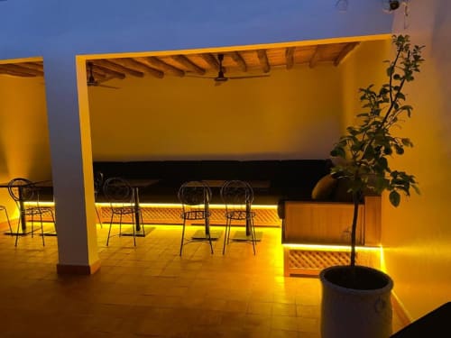 Evening terrace at Riad Madinina in Marrakech with warm lighting, metal chairs, and potted plant under wooden pergola