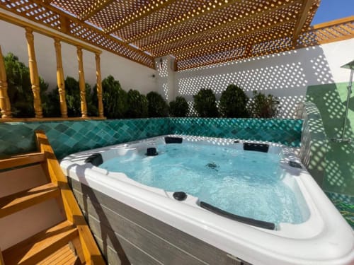 Luxurious hot tub with turquoise tile at Riad Madinina, Marrakech, featuring wooden pergola and lounge chairs