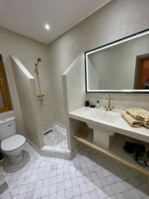 Modern bathroom at Riad Madinina with walk-in shower, illuminated mirror, and white tile flooring in Marrakech