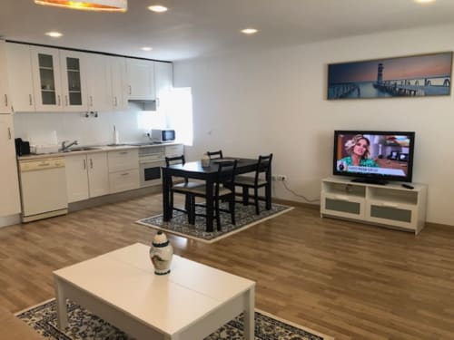 Apartamento em plano aberto em Sintra Apartamentos com cozinha moderna, sala de jantar com mesa preta, sala de estar com TV e