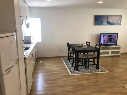 Cozinha em plano aberto e área de refeições no Apartamento Sintra com mesa de jantar, TV e eletrodomésticos modernos
