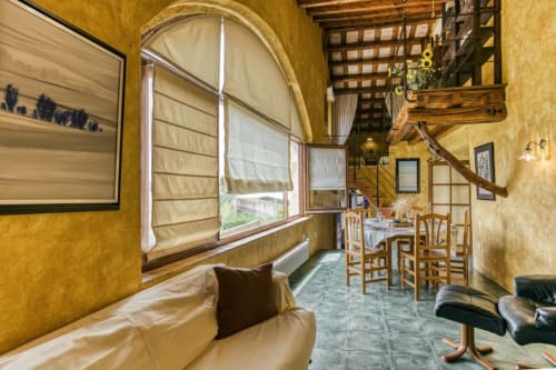 Acogedor salón rústico en la casa rural Can Gat Vell en Girona, Empordà, con sofá de cuero crema y muebles de madera
