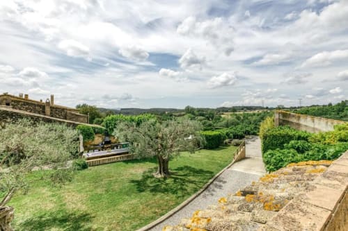 Jardín en terrazas de piedra con olivos, césped verde y vistas a la campiña de Empordà, Cataluña