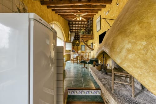 Pasillo rústico de la casa rural Can Gat Vell en Girona, Empordà, con paredes mostaza, vigas de madera y decoración catalana tradicional