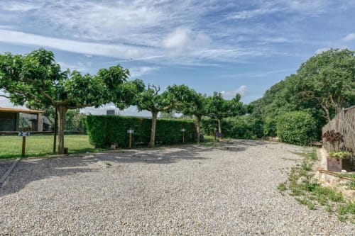 Amplio patio de grava en Can Gat Vell B&B en Girona con árboles maduros y zonas de césped verde bajo cielo azul
