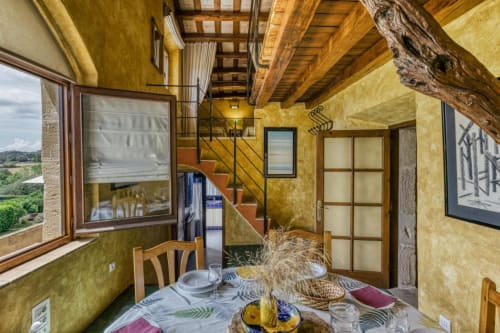 Comedor rústico del alojamiento Can Gat Vell B&B en Girona con vigas de madera, paredes amarillas y vistas al campo