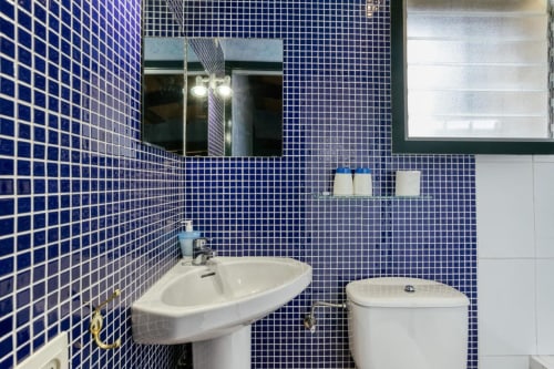 Baño moderno con azulejos de mosaico azul, lavabo y inodoro blancos en el Can Gat Vell B&B en Girona, Cataluña