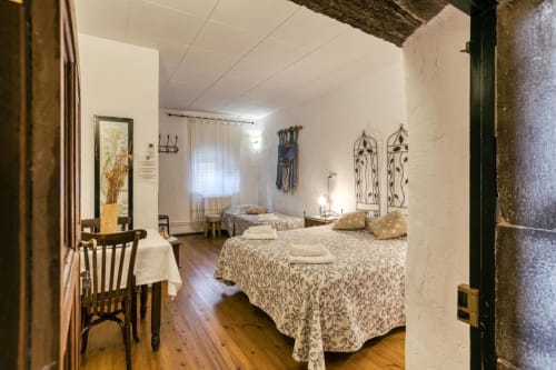 Dormitorio rústico en el B&B Can Gat Vell de Girona con camas gemelas, vigas vistas y decoración catalana tradicional.