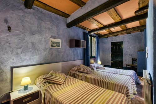Camas gemelas con ropa de cama a rayas en una habitación rústica de Can Gat Vell, casa rural boutique en Girona, Empordà-Catalunya