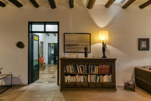 Sala de estar de la biblioteca Can Gat Vell en Girona con estanterías de madera, lámpara y vigas expuestas