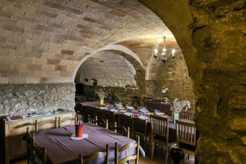 Comedor medieval en Can Gat Vell con techos abovedados, mesas rústicas y candelabros en Girona, Cataluña